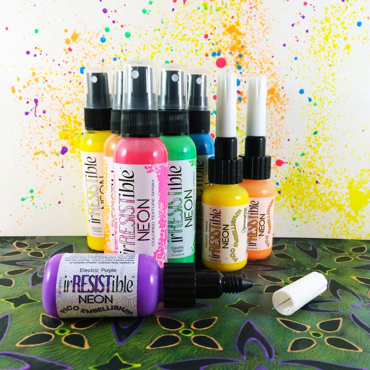 Multiple bottles of irRESISTible spray bottles and Pico Embellishers with a colorful background created using he product.