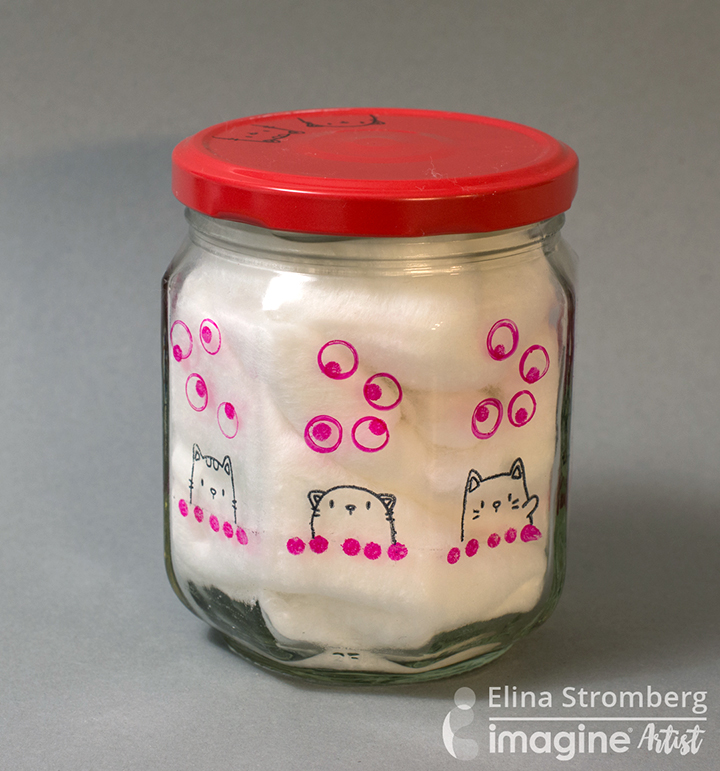 An upcycled jam jar decorated with cat stamps using StazOn ink, filled with cotton balls.