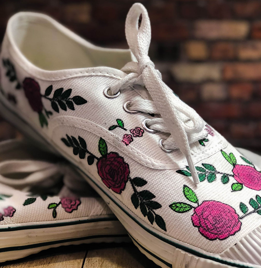 A self adorned pair of canvas shoes in a floral pattern and pink colors